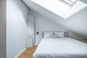 a bedroom with a white bed and a skylight at City Pop Prague Aparthotel in Prague