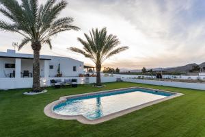 an image of a backyard with a swimming pool and palm trees at Villa Oasys in Almería
