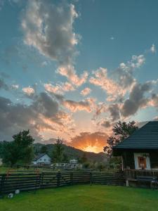 einen Sonnenuntergang über einem Hof mit einem Zaun und einem Haus in der Unterkunft La căsuța cu amintiri in Vama