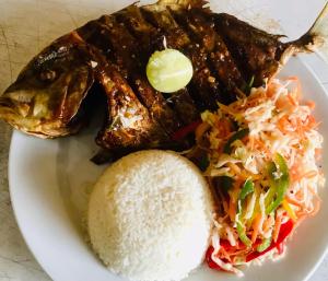 un piatto di cibo con riso e un pesce di Seafood king hostel a Nilaveli