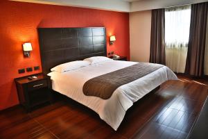 - un grand lit dans une chambre d'hôtel aux murs rouges dans l'établissement Hotel Victoria Inn, à San Juan del Río