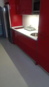 czerwona kuchnia ze zlewem i czerwonymi szafkami w obiekcie Apartamento Mercedes Céntrico Playa w mieście Sanlúcar de Barrameda +8 zdjęć