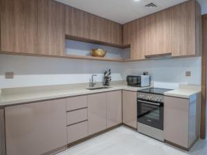 a kitchen with white counters and wooden cabinets at Aven Apartment Dubai 2BR-2209 in Urban Oasis by Missoni-Business Bay Dubai in Ghantoot