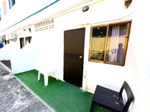 un edificio blanco con puerta negra y suelo verde en Patong Canal Villa 107, en Patong Beach