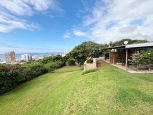 a house with a grassy yard next to a building at Beachbreak Cottages in Durban