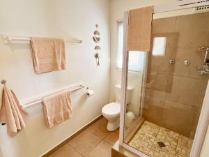 a white bathroom with a shower and a toilet at Beachbreak Cottages in Durban +41 photos