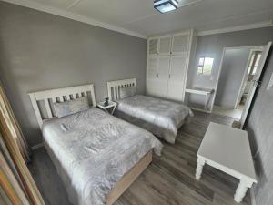 Un dormitorio con dos camas y una mesa. en Barefoot Self-Catering Holiday Home, en Morganʼs Bay