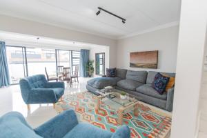 een woonkamer met een bank, stoelen en een tafel bij The Sapphire in Gqeberha