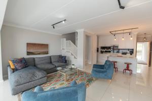 een woonkamer met een bank en stoelen en een keuken bij The Sapphire in Gqeberha