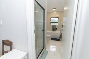 een badkamer met een glazen douche en een toilet bij The Sapphire in Gqeberha +46 foto's