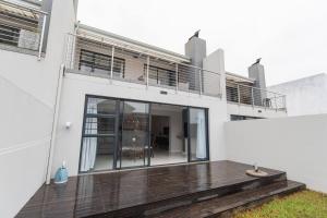 een wit huis met een houten terras ervoor bij The Sapphire in Gqeberha