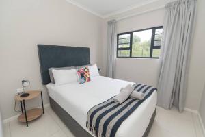 een witte slaapkamer met een bed en een raam bij The Sapphire in Gqeberha