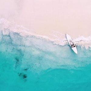 a surfboard in the water next to a wave at Jeeva Beloam Beach Camp in Tanjung Ringgit