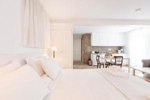 a white bedroom with a white bed and a kitchen at Ventoura Suites, Corfu Old Town in Corfu