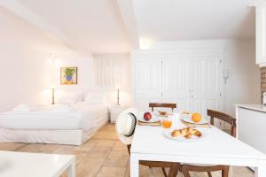 a white room with two beds and a table with a plate of food at Ventoura Suites, Corfu Old Town in Corfu