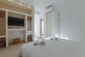 a white bedroom with a bed with towels on it at Art of Filoxenia with swimming pool in Andiparos