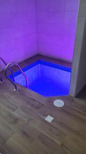a hot tub in a room with a purple wall at KOLO Котеджний комплекс in Tatariv