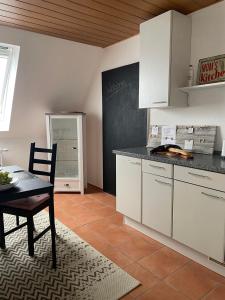 a kitchen with white cabinets and a table and a chalkboard at Ferienwohnung Heinz in Sankt Wendel