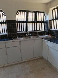 a kitchen with white cabinets and a sink and windows at RUWAMU Guesthouse in Naivasha