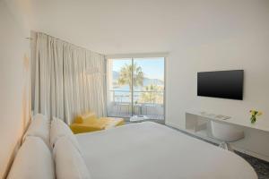 a white hotel room with a bed and a television at nhow Marseille in Marseille