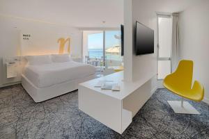 a bedroom with a bed and a tv and a yellow chair at nhow Marseille in Marseille