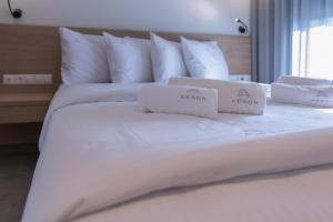 a white bed with two towels on top of it at Aeson Premium Living in Volos