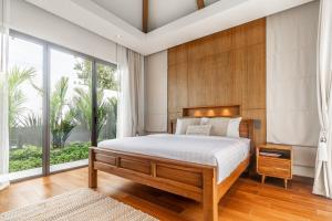 a bedroom with a large bed and a large window at Anchan Flora by Villacarte in Ban Phru Champa