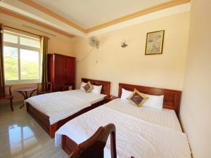 Una habitación de hotel con dos camas y una ventana. en Trung Hậu Hotel, en Con Dao