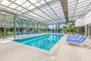 a pool with blue lounge chairs and a building with windows at Sural Hotel in Side