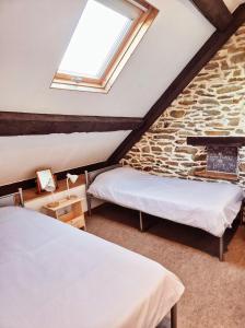 a attic bedroom with two beds and a window at La Maison Neuve Gîtes in Madré +64 photos