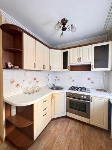 a kitchen with white cabinets and a sink at Apartment on Bukhar Zhyrau in Karagandy