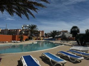 a swimming pool with lounge chairs in a resort at Mobile home Le Badwill2 in Canet-en-Roussillon