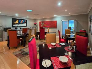a dining room with tables and red chairs at Sunrise Serenity Guest House in Lydenburg +37 photos