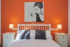 a bedroom with a white bed with an orange wall at Bonito apartamento cerca de Plaza España in Barcelona