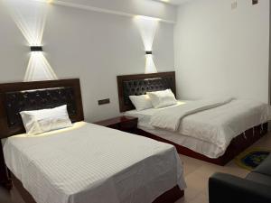 two beds in a hotel room with lights on them at Hotel Green Land in Bāndarban