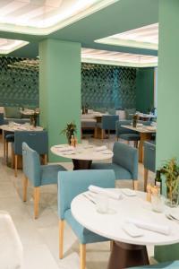 a restaurant with white tables and blue chairs at Hospes Amérigo, Alicante, a Member of Design Hotels in Alicante