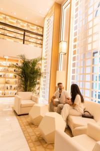 a man and woman sitting on a couch in a living room at Hospes Amérigo, Alicante, a Member of Design Hotels in Alicante