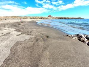 a beach with sand and the ocean on a cloudy day at Mucha Vida in Abades