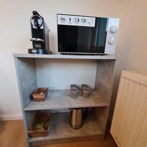 a microwave sitting on top of a shelf with cups at Sarahs Village Apartments in Ottnang am Hausruck