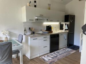 Maison dans la Pinède à Lacanau في لاكانو: مطبخ بخزائن بيضاء وثلاجة سوداء +7 صور