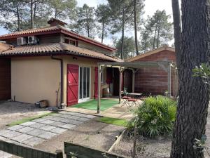 Maison dans la Pinède à Lacanau في لاكانو: منزل صغير مع باب احمر وفناء