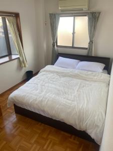 a bedroom with a large white bed with two windows at 静佳民宿 in Osaka +2 photos