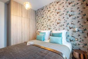 ein Schlafzimmer mit einem großen Bett und einer Wand mit Vogelmuster in der Unterkunft My Cottage in Paris in Paris