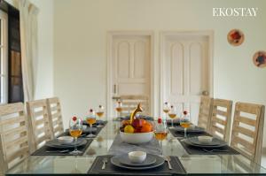 a dining room table with a bowl of fruit and wine glasses at EKOSTAY - Ezra Villa in Anjuna