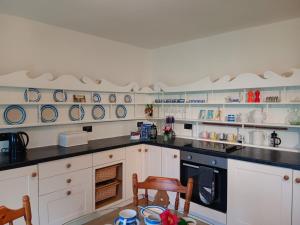 una cucina con armadi bianchi e piatti blu sul muro di Pandia Cottage a Bodmin