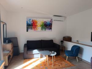 a living room with a couch and a painting on the wall at Charmant T2 au calme in Vidauban