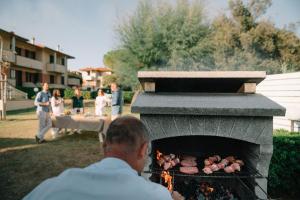 a man sitting in front of an outdoor grill at Villaggio Mietta in Castiglioncello