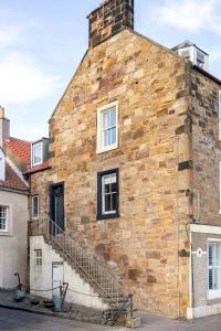 an old brick building with stairs on it at Ledgers Cottage- Harbourfront Home Pittenweem in Pittenweem