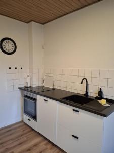 a kitchen with a sink and a clock on the wall at Ferienwohnung Meeresglück in Kruså +15 photos