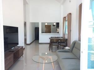 a living room with a couch and a glass table at บ้านสวนสุรัชฎา ปาย in Kampong Huaibū